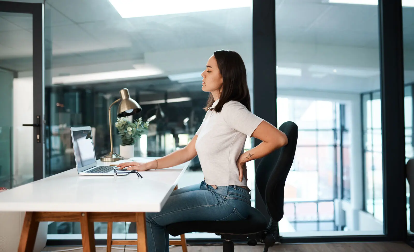 Person experiencing upper back pain at a desk