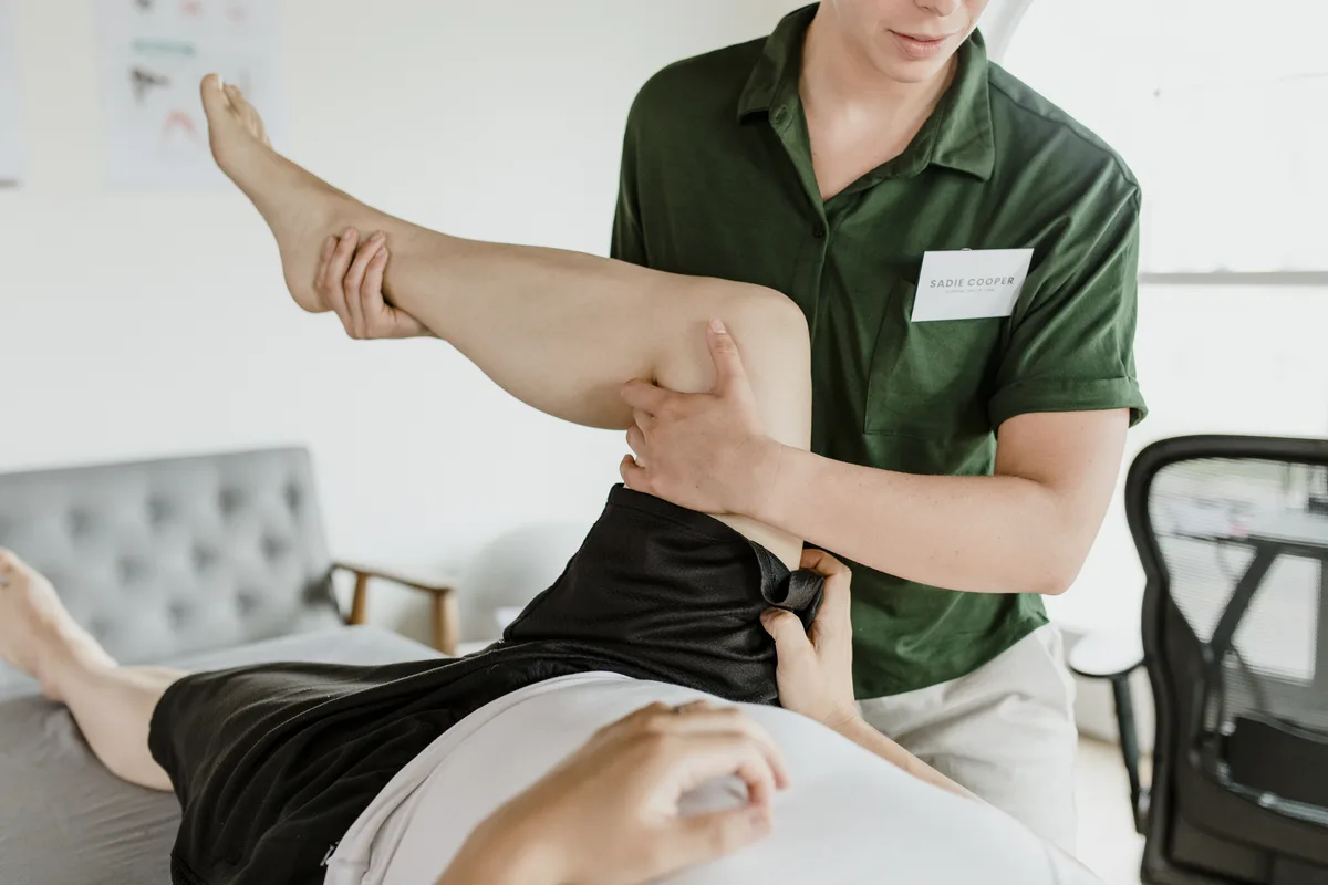 Physiotherapist guiding a patient's raised leg during sciatica rehabilitation