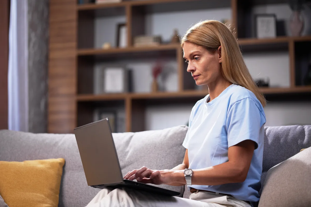 Woman using a laptop at home to describe her symptoms to PhysioMatch